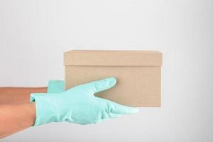 consegna di un' pacco con guanti per protezione contro virus e malattie su un' bianca sfondo. foto