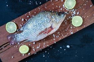 pesce tilapia fresco su tavola di legno
