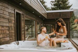 giovane coppia godendo nel all'aperto caldo vasca su vacanza foto