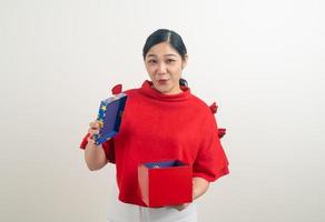donna asiatica felice che indossa una maglietta rossa con una confezione regalo a portata di mano per il festival di natale foto