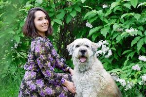 ritratto di bellissimo giovane donna con Sud russo pastore cane su un' sfondo di estate parco con fioritura lilla cespugli. foto