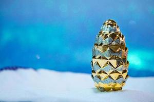 allegro Natale giocattolo d'oro cono su il neve e blu cielo a partire dal dietro. sfocato sfondo. nuovo anno carta. copia spazio foto