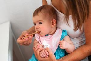 madre alimentazione carino bambino ragazza verdura puré a partire dal un' cucchiaio. salutare mangiare nutrizione per poco bambini foto