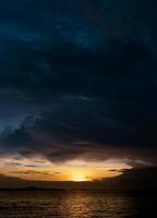 tramonto crepuscolo cielo nel sera con arancione, giallo e buio blu colore di il mare, mare con drammatico crepuscolo paesaggio di orizzonte e nuvola, verticale romantico Alba nel estate foto