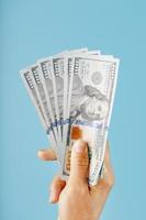 batuffolo di banconote nel mano su un' blu sfondo. il concetto di finanziario assistenza. foto