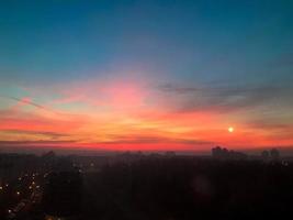 bellissimo rosso alba di il sole nel un' grande città metropoli con edifici e nuvole. il Visualizza a partire dal il altezza foto