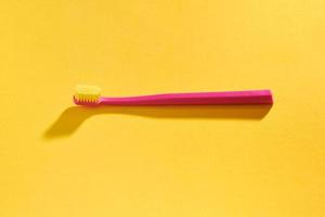 spazzolino rosa su sfondo giallo per l'igiene orale per pulire denti, gengive e lingua foto