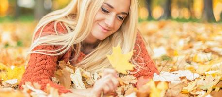 donna bugie giù su le foglie a il autunno parco foto