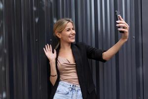 donna imprenditore parlando su video chiamata utilizzando smartphone nel ufficio su grigio parete sfondo foto