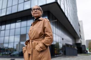 riuscito anziano cittadino donna testa su il sfondo di il facciata di un' moderno ufficio edificio foto