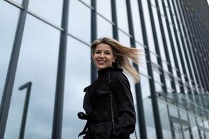 donna donna d'affari con volante capelli nel il vento contro il fondale di un ufficio edificio foto