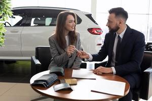 maschio manager vendita un' nuovo auto per un' giovane donna nel un' auto concessionaria, auto noleggio concetto foto