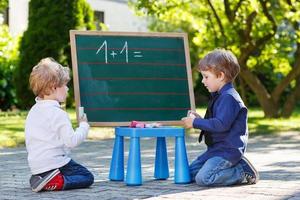 due ragazzi siblinig alla lavagna che praticano matematica