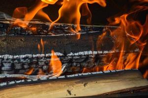 di legno ardente caldo carbonizzato tavole di legna logs nel un' fuoco con lingue di fuoco e Fumo. struttura, sfondo foto