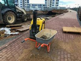 carrello per trasporto pesante materiali, calcestruzzo, mattoni e sabbia. Il prossimo per il macchina per il produzione di strada superfici. contro il sfondo di il ruote di un' bruco trattore foto