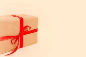 Natale regalo scatola con rosso arco su beige sfondo. vacanza concetto, nuovo anno regali. foto