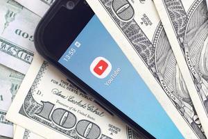 Kharkiv, Ucraina - Maggio 2, 2021 smartphone schermo con Youtube App e lotto di centinaio dollaro fatture. attività commerciale e sociale networking concetto foto