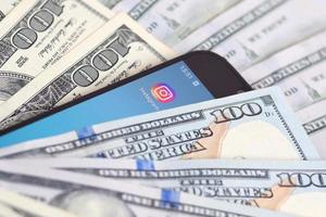 Kharkiv, Ucraina - Maggio 2, 2021 smartphone schermo con instagram App e lotto di centinaio dollaro fatture. attività commerciale e sociale networking concetto foto