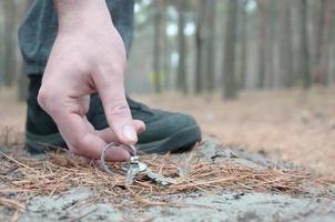 maschio mano raccolta su perso chiavi a partire dal un' terra nel autunno abete legna sentiero. il concetto di scoperta un' prezioso cosa e bene fortuna foto