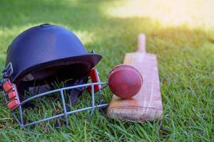 cricket attrezzatura è un' cricket sfera, cricket pipistrello, cricket casco su un' erba sfondo. morbido e selettivo messa a fuoco. foto