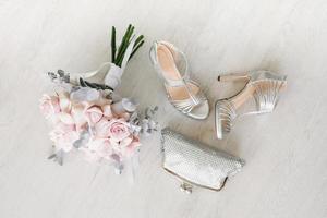 nozze Accessori per il sposa, un' mazzo di rosa Rose, borse e scarpe su il sfondo foto