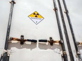 Segnale di pericolo di radiazioni sull'etichetta di trasporto di merci pericolose classe 7 presso il contenitore del camion di trasporto foto
