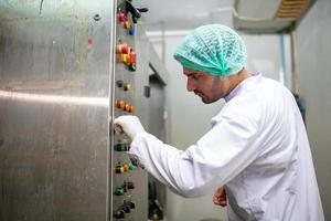 lavoratore è controllo operativo macchina e girare su interruttore su il produzione linea nel il bevanda fabbrica. foto