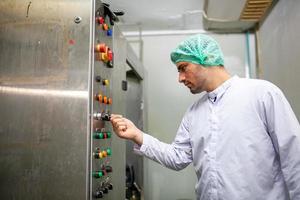 lavoratore è controllo operativo macchina e girare su interruttore su il produzione linea nel il bevanda fabbrica. foto