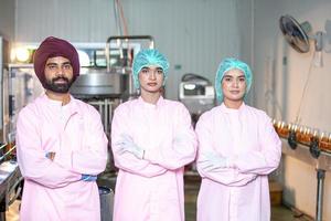 gruppo di asiatico lavoratore con appunti è controllo Prodotto bottiglie di frutta succo su il produzione linea nel il bevanda fabbrica. fabbricante controlli qualità di cibo industria. foto