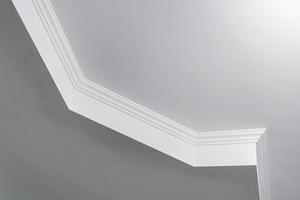 dettaglio di angolo soffitto con intricato corona modanatura. sospeso soffitto e cartongesso costruzione nel vuoto camera nel appartamento o Casa. allungare soffitto bianca e complesso forma. foto