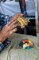 artigiano chi vernici con il suo dita su il strada e crea paesaggi Messico, Guadalajara foto