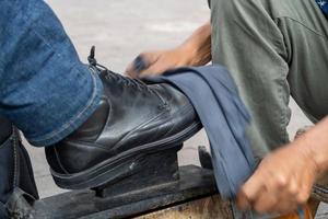 scarpe nel un' lavare bacino con insaponato acqua. pulizia il scarpe a strada, latino vecchio uomo, foto