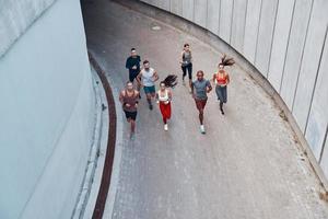 superiore Visualizza di giovane persone nel gli sport capi di abbigliamento jogging mentre esercizio all'aperto foto