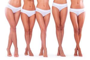 bellissimo gambe. avvicinamento di cinque donne indossare mutandine e mostrando loro Perfetto gambe mentre in piedi contro bianca sfondo foto