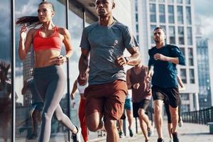 gruppo di persone nel gli sport capi di abbigliamento jogging mentre esercizio su il marciapiede all'aperto foto