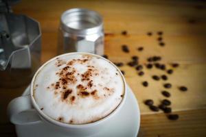 caldo cappuccino nel bianca tazza con di legno sfondo, caffè è un' popolare bevanda tutti al di sopra di il mondo. foto