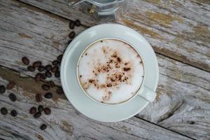 caldo cappuccino nel bianca tazza con di legno sfondo, caffè è un' popolare bevanda tutti al di sopra di il mondo. foto