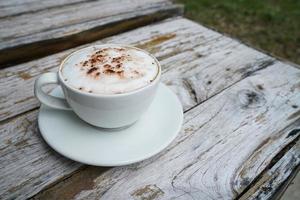 caldo cappuccino nel bianca tazza con di legno sfondo, caffè è un' popolare bevanda tutti al di sopra di il mondo. foto