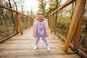 bambino ragazza in posa a di legno ponte nel autunno foresta. foto