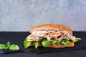 appetitoso Sandwich con pasticcini, cetriolo, formaggio e basilico su il tavolo. copia spazio foto