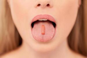 pillola su sua lingua. avvicinamento di giovane donna Tenere pillola su sua lingua foto