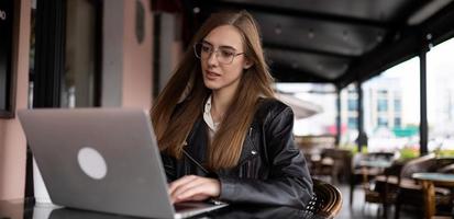 donna libero professionista Lavorando in linea su il computer portatile nel città bar foto