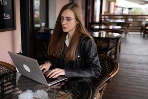 giovane donna Lavorando su un' il computer portatile nel un' città bar foto