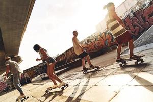 essi conoscere Come per pattinare. pieno lunghezza di giovane persone andare con lo skateboard mentre sospeso su a il pattinare parco all'aperto foto