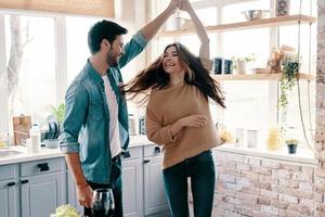 nel amore. bellissimo giovane coppia nel casuale capi di abbigliamento danza e sorridente mentre in piedi nel il cucina a casa foto