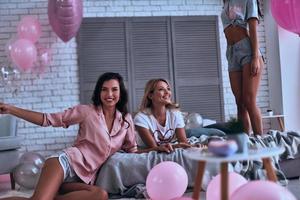 festa per ragazze solo. tre amiche nel pigiama bonding insieme mentre la spesa tempo nel il Camera da letto foto