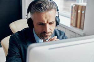 avvicinamento di uomo d'affari nel cuffie avendo ragnatela conferenza mentre seduta a il suo Lavorando posto foto