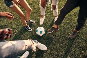 avvicinamento di giovane persone nel casuale indossare giocando calcio mentre la spesa tempo all'aperto foto