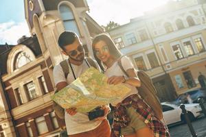bellissimo giovane coppia guardare a carta geografica e sorridente mentre in piedi all'aperto foto