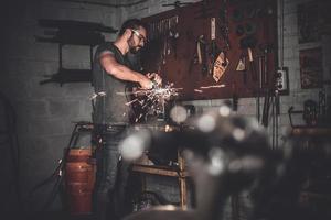 opera per vero uomini. fiducioso giovane uomo macinazione con scintille nel riparazione negozio foto